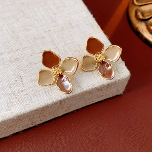Macro shot of vintage enamel flower earrings in caramel and beige with gold metal edges