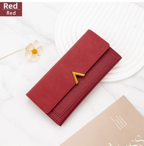 Detail of red PU leather long wallet with golden V-shaped metal buckle on marble surface