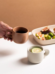 Close-up of matte ceramic coffee mugs in brown and beige with minimalist lifestyle setting