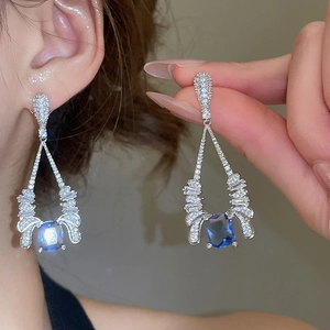 Detail of elegant silver drop earrings with a square blue gemstone and white zircon accents