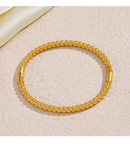 Macro detail of golden bead bracelet with polished metallic finish and cylindrical clasp