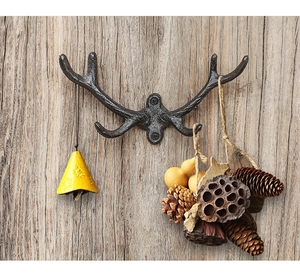 Detail view of rustic cast iron antler wall hook with screws on wooden surface