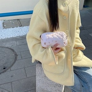 Quilted pink cylindrical pouch with cute bear patterns held by a model in natural light