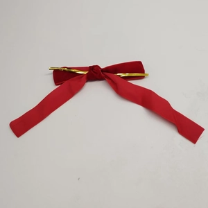 Detail of a red velvet Christmas bow with gold metallic wire tie for holiday decoration