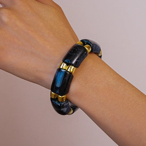 Detail of marble pattern acrylic bangle with gold accents on model wrist