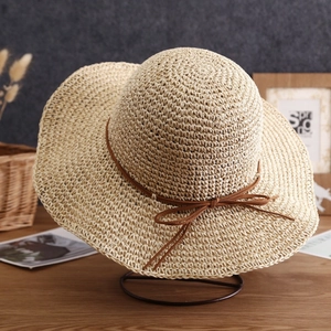 Detailed close-up of handmade straw sun hat texture with brown ribbon bow decoration