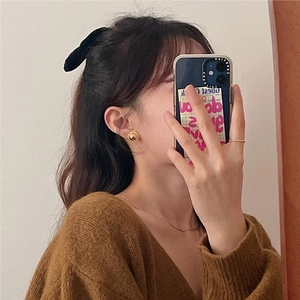 Mirror selfie showing elegant gold ball stud earrings paired with a cozy brown knit sweater