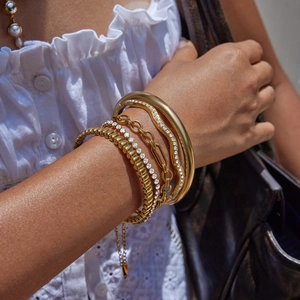 Gros plan de bracelets superposés en acier inoxydable plaqué or 18 carats sur un mannequin
