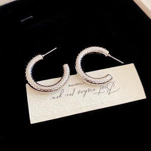 Detailed view of silver C-shaped hoop earrings with dotted texture on black velvet