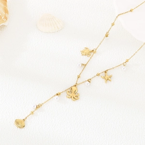 Detail of golden ocean-themed necklace with starfish, turtle charms and white pearls