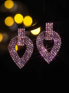 Close-up of luxury heart-shaped drop earrings featuring pink crystals and tassels