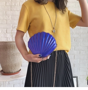 Detail of shell-shaped evening bag with blue-purple pearlescent finish and pearl charm