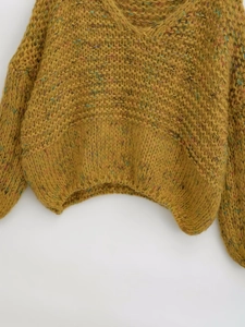 Detail of space-dyed chunky knit sweater showing ribbed hem and mustard yellow yarn texture