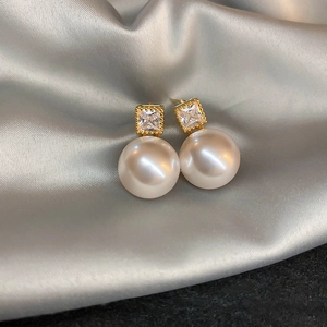 Detail of vintage gold pearl earrings with shimmering crystals on smooth silk fabric