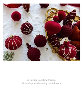 Detailed view of burgundy velvet Christmas ornaments with gold glitter on white snow