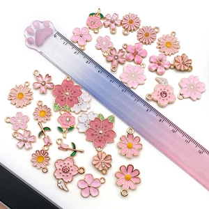 Close-up of pink cherry blossom and daisy enamel charms with a measurement ruler