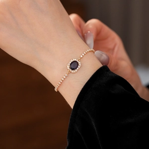 Close-up of golden zircon bracelet with purple oval gemstone worn on a wrist