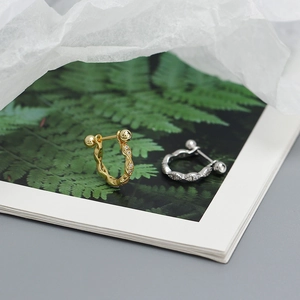 Detail of twisted s925 silver stud earrings with crystals on an artistic background