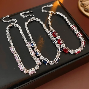 Detailed view of silver bracelets with pink, blue and red zircon stones on black leather