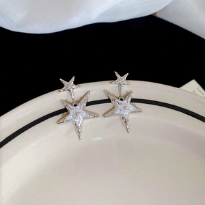 Detailed macro view of silver star earrings with sparkling cubic zirconia on white silk
