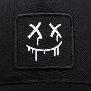 Detailed macro shot showing the melting smile face embroidery on a black baseball cap
