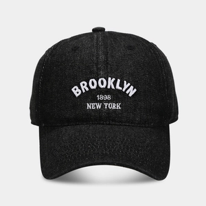 Détail de la broderie blanche Brooklyn 1898 sur le tissu denim noir de la casquette