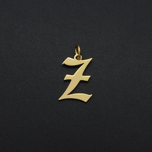 Macro detail of golden metal Z letter pendant with small hoop on dark textured background