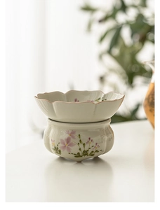 Detail view of a hand-painted ceramic tea strainer with elegant pink floral patterns