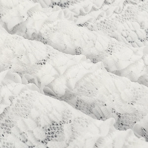 Macro detail of delicate white lace fabric showing intricate mesh patterns and textures