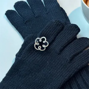 Close-up of black knitted gloves featuring elegant silver hollow flower metal charms