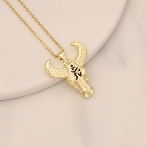 Detail view of gold bull skull pendant with zircon inlay and black etched texture