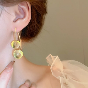 Close-up of translucent light green drop earrings with long gold hooks on model