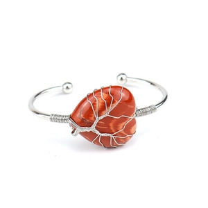 Macro detail of red jasper heart stone with silver wire tree of life on copper bracelet