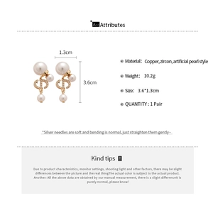 Detail view of CD logo stud earrings with cubic zirconia and teardrop pearls