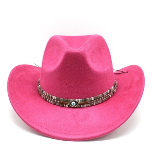 Pink suede cowboy hat with evil eye charm and textured band detail on white background