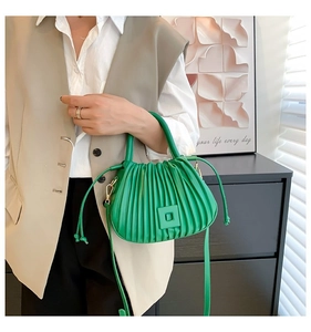 Detail of emerald green pleated bucket bag with vertical texture and stylish square decor