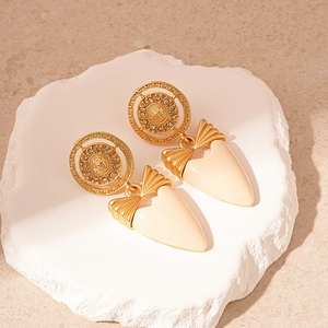 Boucles d'oreilles vintage cœur et nœud en or et émail blanc posées sur une pierre