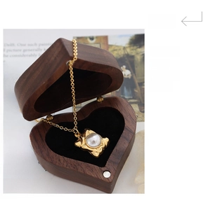 Detail of vintage gold necklace with pearl pendant in a wooden heart jewelry box