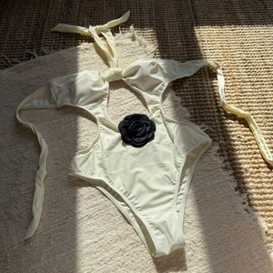 Detail of a cream cutout swimsuit featuring a 3D black camellia floral embellishment