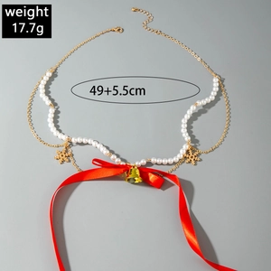 Detailed view of Christmas pearl necklace with red bow and gold snowflake pendants