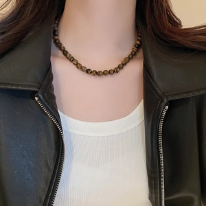 Maillard tiger eye beaded necklace on model with white top and black leather jacket