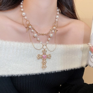 Detail of multi-layered pearl necklace with rhinestone cross and pink heart gemstone