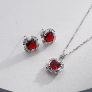 Detailed macro shot of silver necklace and earrings set with red square zircon stones