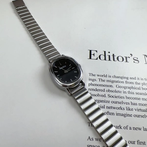 Macro view of silver alloy watch with black oval dial on minimalist book background