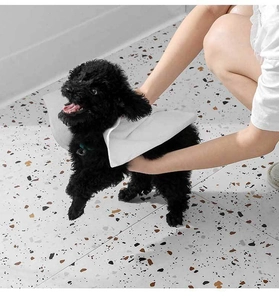 Owner drying a black poodle with a thick white disposable absorbent pet towel