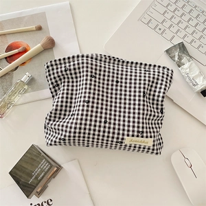 Détail de la trousse à maquillage à carreaux avec broderie florale et étiquette