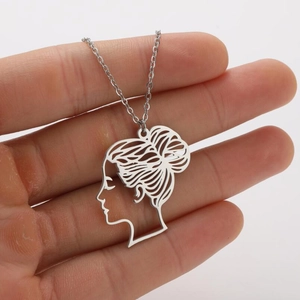 Nahaufnahme einer Edelstahlhalskette mit Mädchen-Silhouette-Anhänger in der Hand