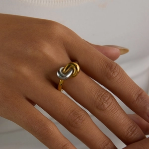 Detail of two-tone stainless steel ring featuring a twisted knot design on finger