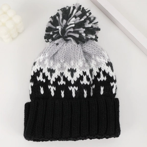 Winter knit beanie with black and white pom-pom and geometric snowflake pattern