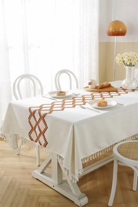 Close-up of geometric embroidery and fringe details on a beige waterproof tablecloth